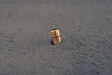 An old shiny bullet driven into the sand