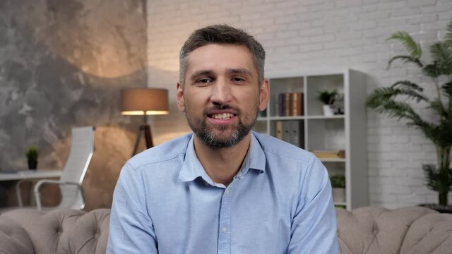 Webcam view smiling man professional trader broker greets listens questions stock market investors. Positive businessman salesman sitting on couch at home office online video call business meeting