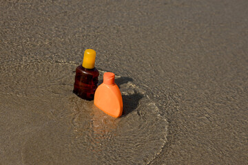 Closeup of sunscreen protection set on sandy beach at tropical seaside on warm sunny day. Skin care concept.