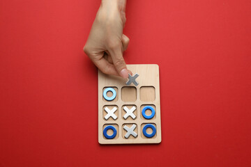 Woman playing tic tac toe game on red background, top view