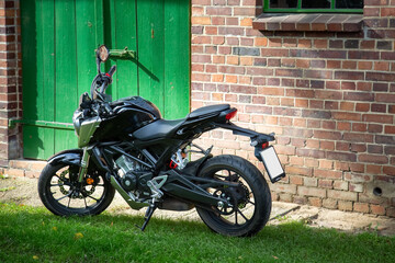 Fototapeta na wymiar Ein Motorrad steht vor einer Scheune mit einem günen Holztor