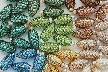 Top down view of green, blue, golden and brown Christmas cones on the white table