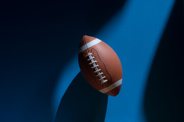 American football ball with natural lighting on blue background. Horizontal sport theme poster, greeting cards, headers, website and app