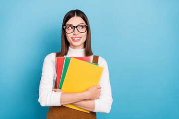 Photo of young lovely girl wondered look empty space minded hold materials isolated over blue color background