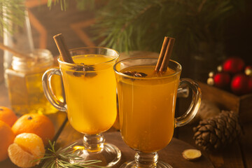 Two glass mugs with sea buckthorn tea. Hot yellow drink with cinnamon sticks and stars of star anise