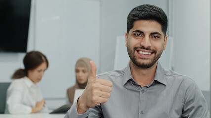 Portrait of happy smiling arab male business leader making thumb up like gesture at camera....