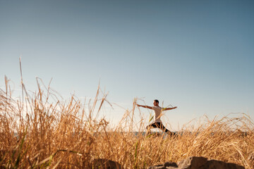 Attractive young man practicing yoga meditation and breath work outdoors by the sea
