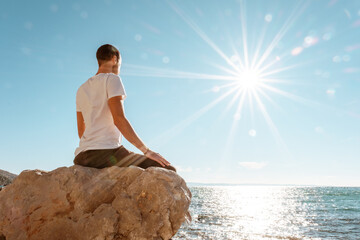 Attractive young man practicing yoga meditation and breath work outdoors by the sea
