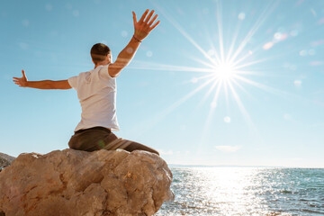 Attractive young man practicing yoga meditation and breath work outdoors by the sea
