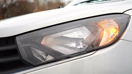 Headlight of gray car close-up with flashing turn signal. Car alarm on. Security signal.