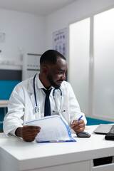 African american therapist doctor looking at computer screen analyzing medical docuemnts with sickness expertise on it. Pysician man working at healthcare treatment in hospital office