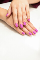 Obraz na płótnie Canvas Beautiful fingers with purple nails after nail polish procedure in manicure salon