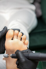 Peeling pedicure procedure on the sole from callus of the female foot by a pedicurist at a beauty salon