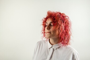beautiful red-haired girl posing on a white background in a white shirt with emotions on her face
