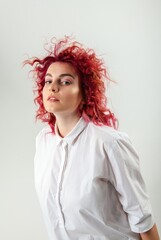 beautiful red-haired girl posing on a white background in a white shirt with emotions on her face