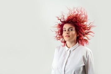 beautiful red-haired girl posing on a white background in a white shirt with emotions on her face