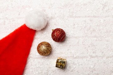 Santa's hat with balls and snowflakes hanging on a snow background.