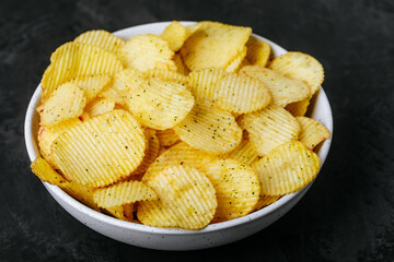 Potato chips. Crispy potato chips and sour cream with onion in bowl on a dark stone concrete background