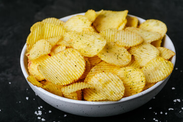 Potato chips. Crispy potato chips and sour cream with onion in bowl on a dark stone concrete background