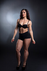 Fototapeta na wymiar Portrait of Strong fitness woman bodybuilder with black hair and tanned body.