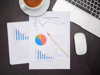 Top view of paperwork, laptop, mouse, and a coffee cup on the desk in the office. Business and strategy concept
