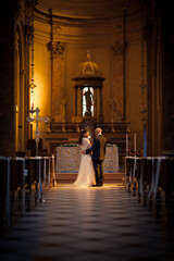 Wedding couple in love stand by altar in church with no people look to each other with smile on...