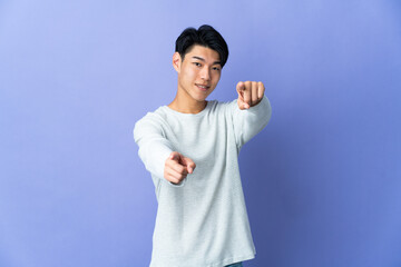 Naklejka premium Young Chinese man isolated on purple background pointing front with happy expression