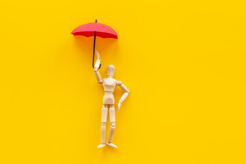 Insurance protection concept with wooden mannequin figure and umbrella