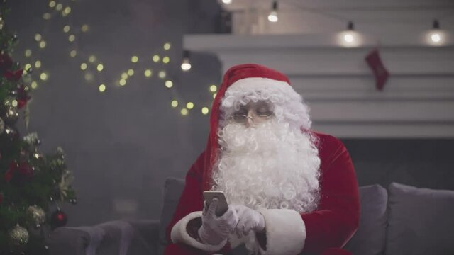 Santa Claus sitting on couch and talking on smartphone