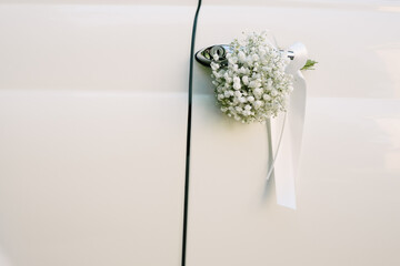 White flowers on the door handle of the car, decoration of wedding retro car