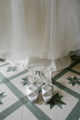 Top view Close up view pair of bridal high heel shoes on stylish floor isolated indoor by white wedding dress on display