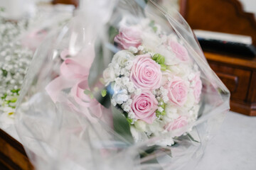 Beautiful wedding bouquet protected in transparent paper on white cloth table