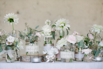 Decorated jars on display with wedding white flowers stand on row on display in wedding venue on weddings day