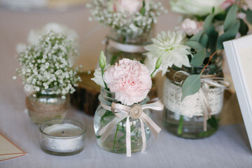 Wedding flower decor corner with white pink flowers in decorated jars on display in natural lightning indoors