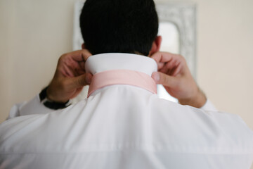 Back view groom getting ready for wedding day fix shirt and pink tie looking at mirror - 471452945