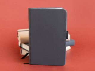 Stack of beige and grey notebooks on red background closeup