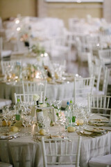 Round wedding table set up with chairs, shiny cutlery; crockery with bouquet flowers in middle on wedding day