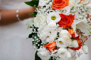 Close up bride hold beautiful white red rose wedding flower bouquet on wedding day outdoors in natural lightning