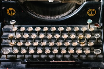 Top view two golden wedding rings separately on old vintage typing machine buttons displayed