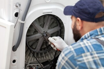 a man repairing a washing machine in cap