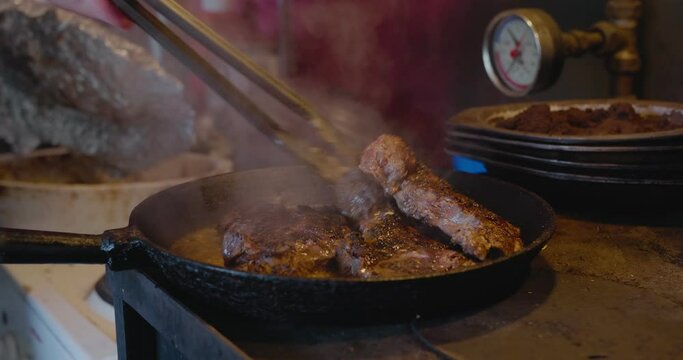 Elder Woman Hand Puts More Meat Onto Iron Pan in Old Countryside Kitchen and Puts Glass Lid On, Handheld Medium Shot