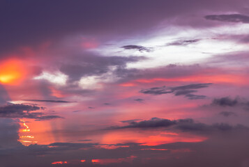 Fototapeta premium The sun shines through the clouds in the sunset sky with dramatic light. The shape of the clouds.