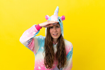 Girl with unicorn pajamas over isolated background looking far away with hand to look something © luismolinero