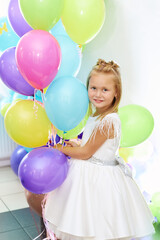 Fototapeta na wymiar A beautiful blonde girl five years old in a white dress is holding balloons. Portrait of a funny child. Children's birthday concept.