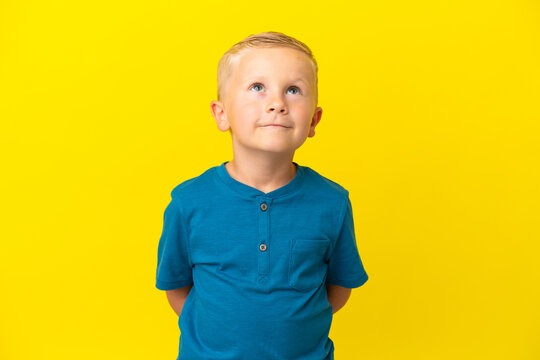 Little Russian boy isolated on yellow background and looking up