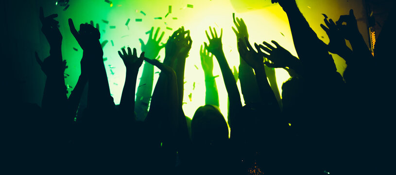 Photo of excited clubbers bachelors raise hands up enjoy show performance event on green bright glitter neon illumination