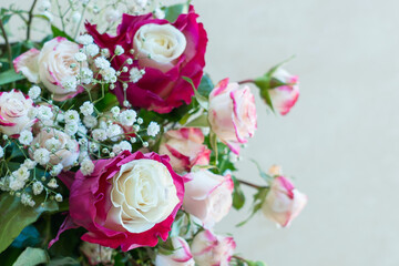 Festive bouquet of white roses with red petals around the perimeter of a white background. Side view, copy space