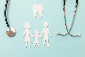 Family health dental care concept. Flat lay stethoscope white healthy tooth family cutout symbol model isolated on blue background. Check up by dentist doctor child. Dental oral hygiene, dentist day