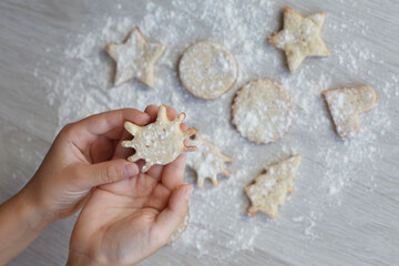 kids Little hands with handmade cookie on wooden table. Christmas gingerbreads, different shapes.