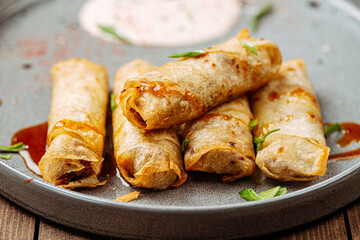 Turkish cigar shaped rolls boreks with sauce on wooden background